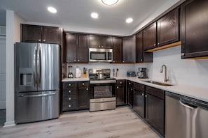 A modern kitchen with stainless steel appliances, dark wood cabinets, and a white tiled backsplash. - Vista Cay 2BR Condo King Suite Near Universal (Orlando)