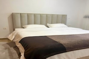 Una habitación de hotel con una cama grande, un cabecero acolchado y una paleta de colores neutros.