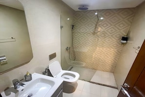 Un baño con inodoro, lavabo y zona de ducha.