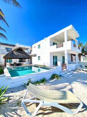 A modern white building with a pool, outdoor seating, and a thatched-roof structure. - New Listing (Progreso)
