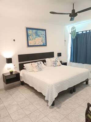 A bedroom with a bed, nightstands, a ceiling fan, a painting, and a window with curtains. - New Listing (Progreso)