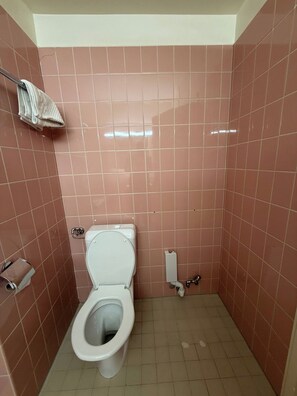 Ein kleines Badezimmer mit Fliesen, einer Toilette, einem Handtuchhalter und einem Papierhandtuchspender.