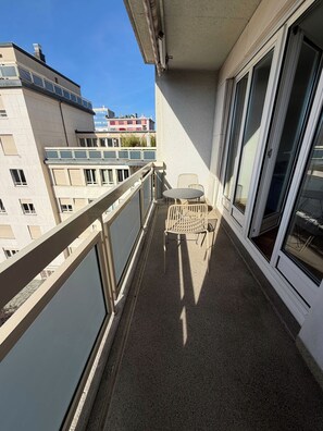 Ein Balkon mit Metallgeländer, einem kleinen Tisch und zwei Stühlen.