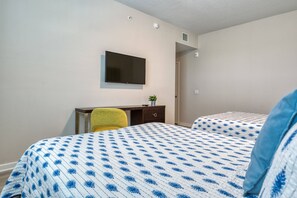 A hotel room with a bed, a desk, a chair, a television, and a door. - Vista Cay 3BR Condo King Suite Near Universal (Orlando)