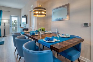 A dining area with a wooden table, blue chairs, and a hanging light fixture. - Vista Cay 3BR Condo King Suite Near Universal (Orlando)