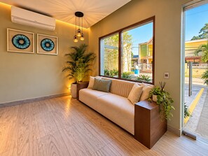 A modern living room with a sofa, a large window, and a potted plant.