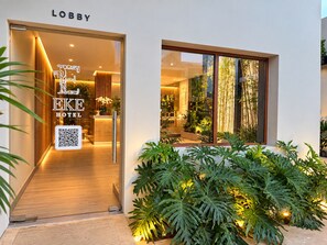 A hotel lobby with a modern design, a reception desk, and a QR code for digital access.