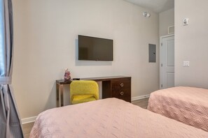 A hotel room with two beds, a TV mounted on the wall, a desk with a chair, and a door. - Vista Cay 3BR Condo King Suite Near Universal (Orlando)
