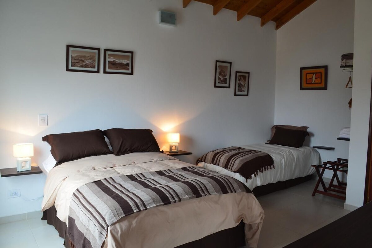 Un dormitorio con dos camas, mesitas de noche y lámparas de pared.