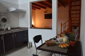 Cocina con armarios oscuros, un lavamanos y ventana con vista a una escalera de madera.