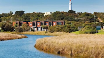 Vista al río con un edificio moderno y un faro al fondo.