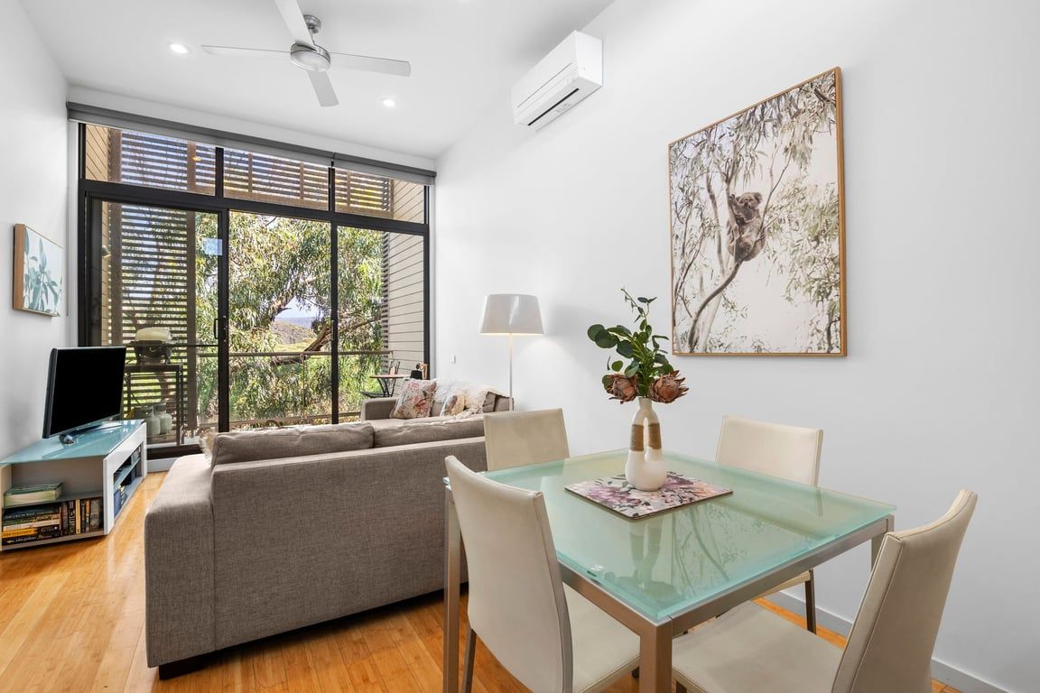 Una sala moderna con una mesa de comedor de vidrio, un sofá y un televisor.