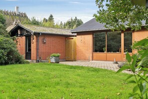 A brick house with a large window, a wooden door, and a small garden. - Holiday home near lake, nature and coast (Faldsled)