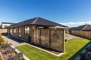 A residential property with a modern design, featuring a covered patio area, a well-maintained lawn, and a wooden fence. - Kopakopa Rest - Taupo (Taupo)