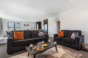 Een moderne woonkamer met twee banken, een salontafel en een keuken op de achtergrond.