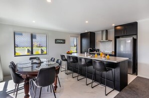A modern kitchen with a central island, black chairs, and a dining table. - Kopakopa Rest - Taupo (Taupo)