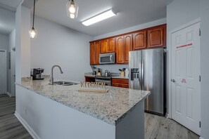 A modern kitchen with granite countertops, stainless steel appliances, and wooden cabinets. - Vista Cay 3BR Condo Pools Near Universal (Orlando)