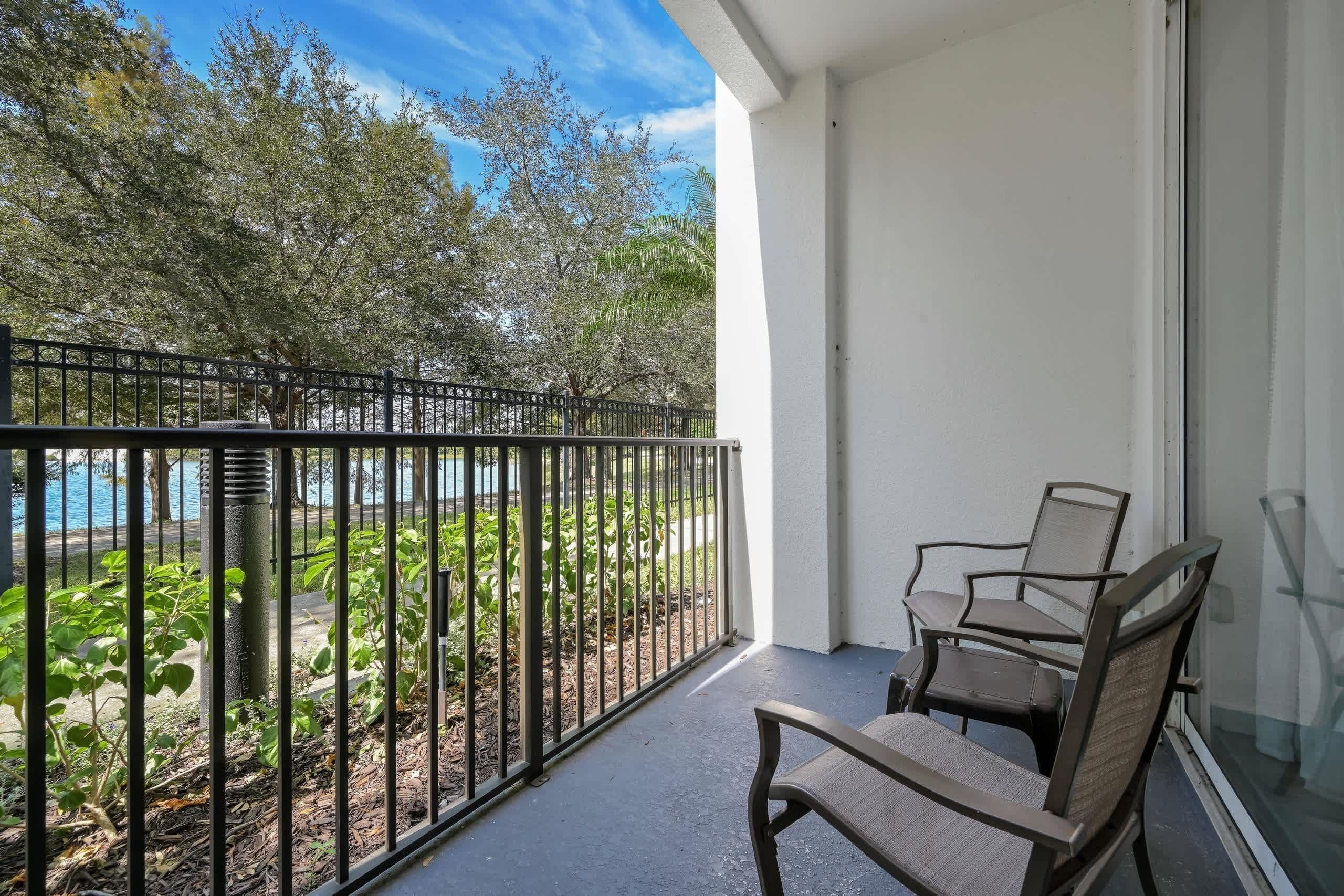 A balcony with a chair and a view of a body of water and trees.