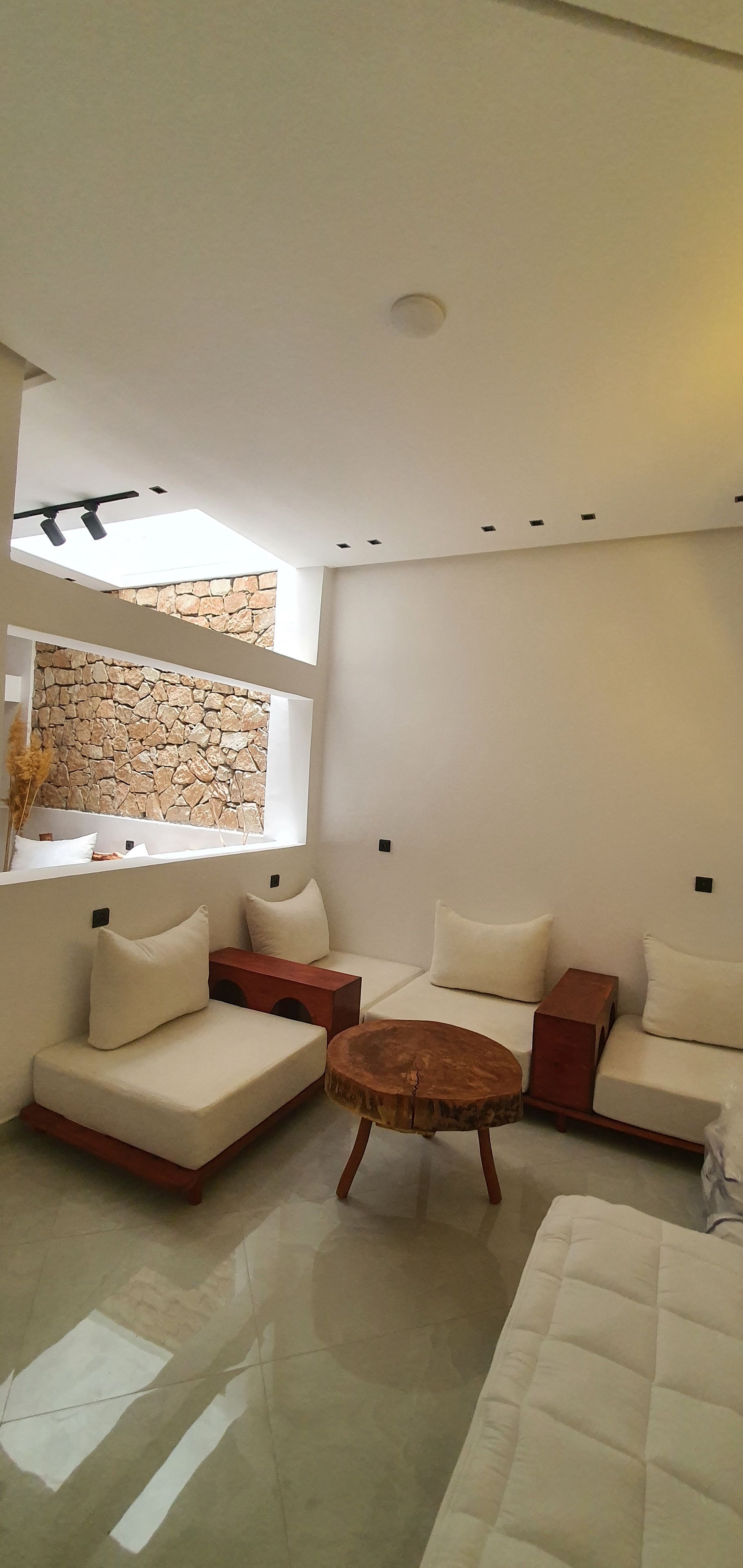 Un soggiorno moderno con parete in pietra, divano, tavolino in legno e finestra con luce naturale.