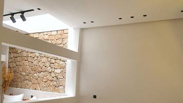 Un soggiorno moderno con parete in pietra, divano, tavolino in legno e finestra con luce naturale.