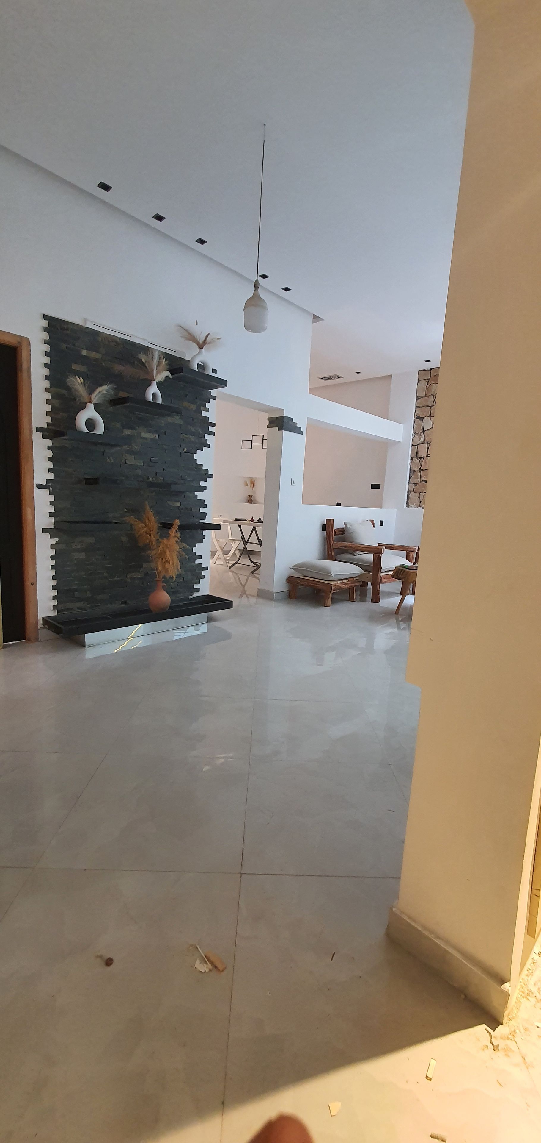Un'ampia stanza dal design moderno, con una parete in pietra, un'area pranzo con tavolo in legno e un soffitto con illuminazione a incasso.
