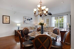 Comedor con candelabro, mesa de comedor para cuatro personas y un sofá al fondo.