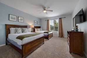 A hotel room with a large bed, a smaller bed, a desk, a television, and a ceiling fan. - Vista Cay 3BR Condo Pools Near Universal (Orlando)