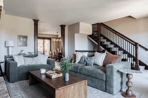 A living room with a sofa set, a coffee table, and a staircase. - Walk to Frostwood Gondola, private hot tub (Park City)