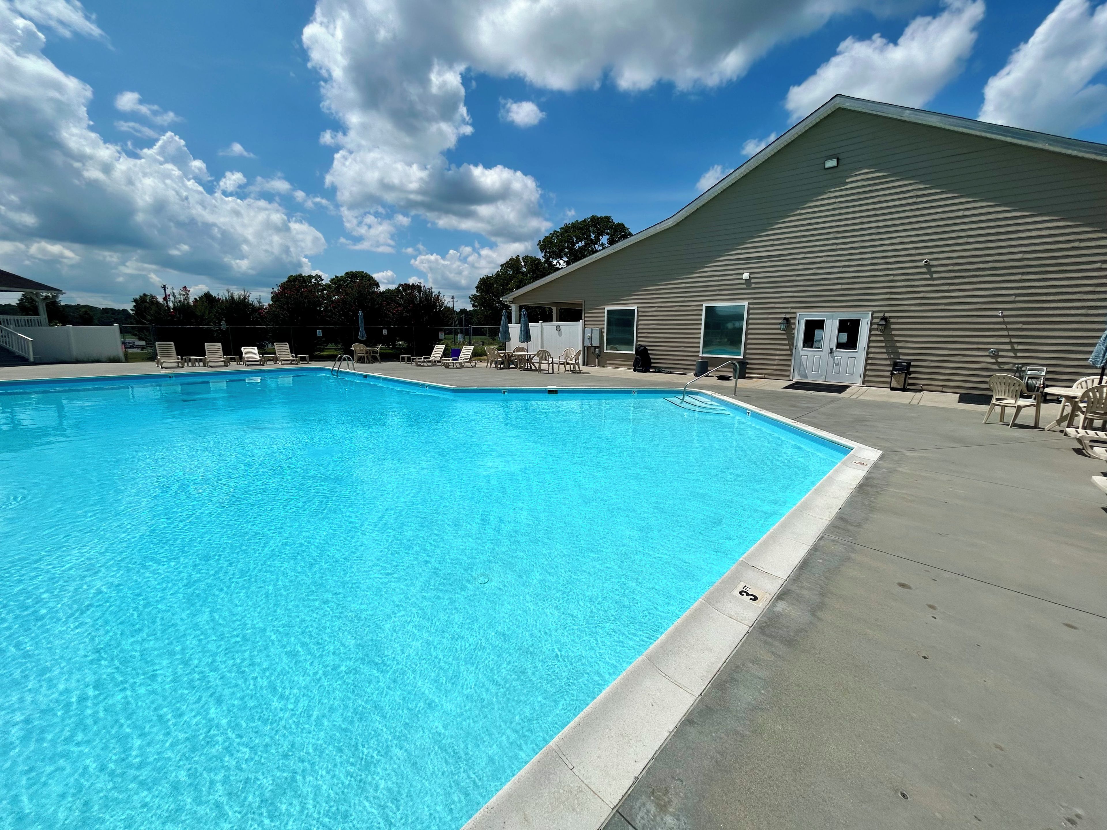 A swimming pool with lounge chairs and a building with large windows.