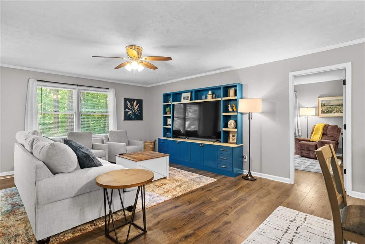 Sit at the round table with the TV wall behind you.