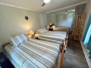 Habitación de hotel con un espejo grande, estructura de cama de madera, mesita de noche con lámpara y una silla de madera.