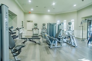 Ett gym med olika typer av träningsutrustning, inklusive löpband och styrketräningsmaskiner.