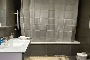 Une salle de bain avec un lavabo blanc, des toilettes et un rideau de douche.