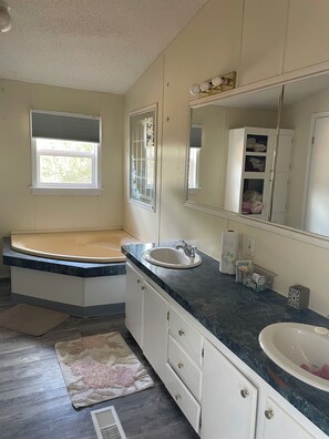 A bathroom with a bathtub, two sinks, a large mirror, and a window. - Mountain home located below Carlito Springs trail and convenient to Albuquerque. (Cedar Crest)
