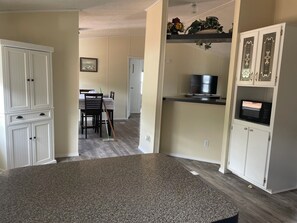 A kitchen with a granite countertop, white cabinetry, a microwave, and a dining area with chairs and a table. - Mountain home located below Carlito Springs trail and convenient to Albuquerque. (Cedar Crest)