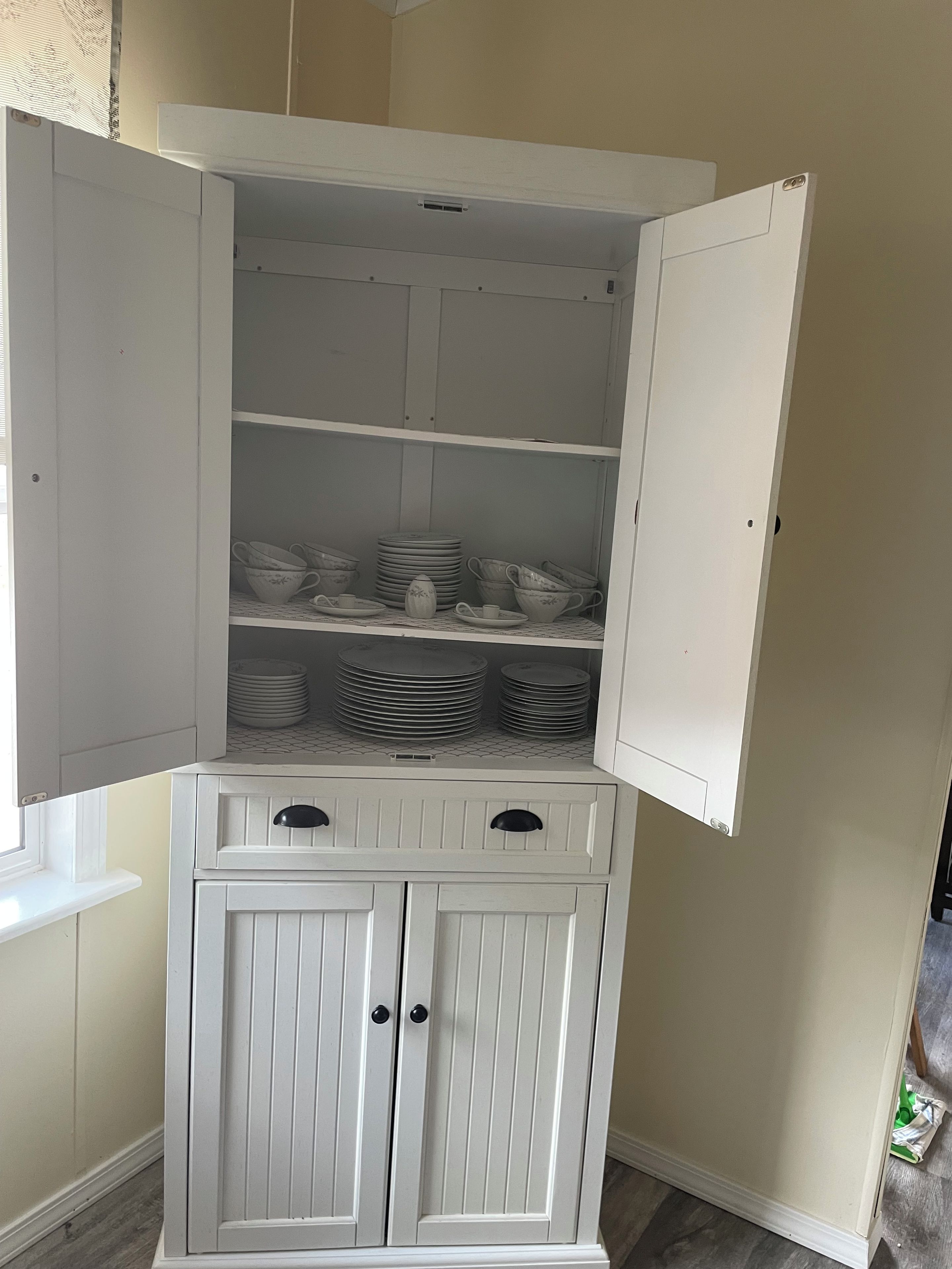 A white storage cabinet with open doors revealing shelves and drawers.