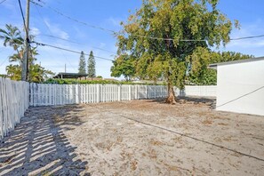 Un pati tancat amb un arbre, un edifici blanc i un cel serè.