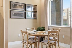 A dining area with a round table, six wooden chairs, and a potted plant. - 4 Suites Near Disney Patio Grill & Balcony (Kissimmee)