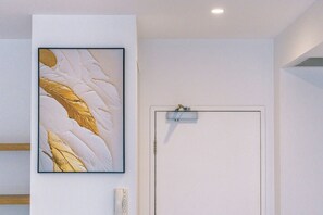 A room with a white door and a framed abstract painting on the wall. - Chic 1 Bedroom Apartment in a Prime Location (Fortitude Valley)
