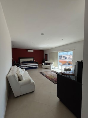 Ein modernes Wohnzimmer mit einer Couch, einem Bett und einem großen Fenster.