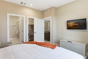 Ein Schlafzimmer mit einem großen Bett, einem Kleiderschrank, einem Spiegel und einem Fernseher auf einem Schrank.