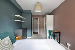 A bedroom with a bed, a desk, a chair, a wardrobe, and a door leading to another room. - Charming Parkside Apartment | WiFi | Gated Parking (Greater London)
