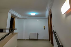 A hallway with a radiator, a light fixture, and a door. - Ground living (Tunis)