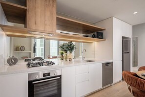 A modern kitchen with a central island, built-in oven, and stainless steel appliances. - Resort-Style 2BR Living with Pool, Gym and Sauna (South Melbourne)