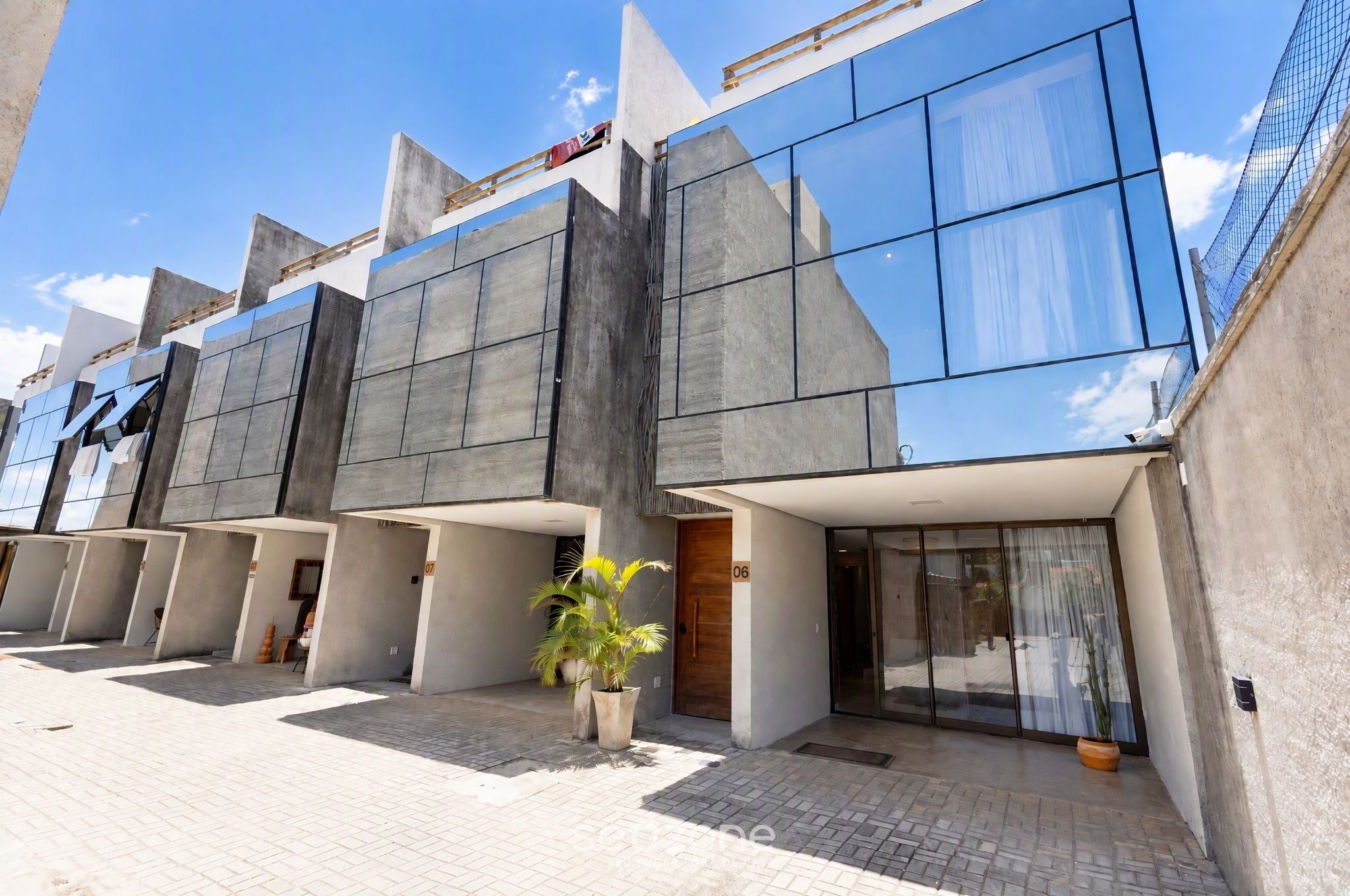 A modern building with a glass facade, multiple entry points, and a paved entrance area.