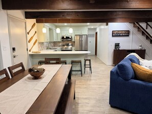 Una cocina moderna con una isla central, mesa de comedor de madera y taburetes de bar.