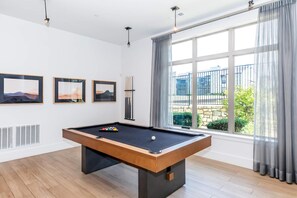 Een biljarttafel in een ruimte met grote ramen, kunst aan de muur en een radiator.