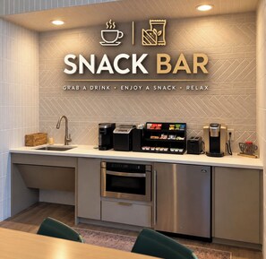Een kitchenette met een koffieapparaat, een broodrooster en een bord met daarop 'snackbar'.