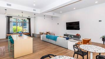 A modern living room with a pool table, a sofa, a coffee table, and a TV mounted on the wall.