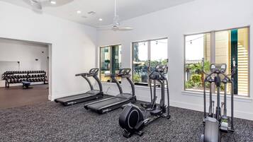 Ein Fitnessraum mit Laufbändern, Crosstrainern und einem Gewichtsständer.